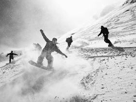 Eine Gruppe von Snowboardern fährt zusammen im verschneiten Gelände
