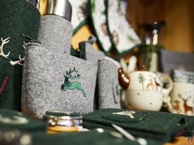 Nahaufnahme von verschiedenen Souvenirs aus grünem und grauen Filz mit Hirsch Stickerei wie Schlüsselanhänger, Flaschenhülle und Geldbörse 