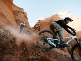 Ein Mann und eine Frau fahren auf Scott E-Bikes einen Trail in felsiger Landschaft hinunter