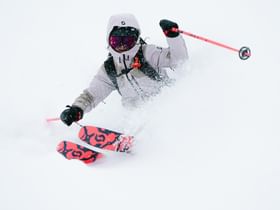 Eine Freeriderin fährt im tiefen Pulverschnee einen steilen Hang hinunter