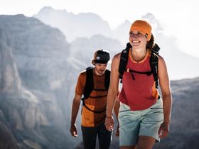 Eine Frau und ein Mann wandern in Ortovox Bekleidung in einer alpiner Berglandschaft