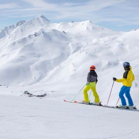 Zwei Skifahrer stehen am Rande einer Piste und blicken ins tief weiße Masner Skigebiet in Serfaus