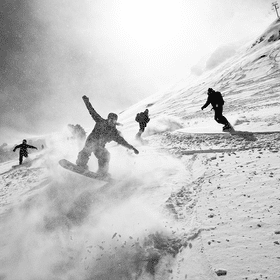 Eine Gruppe von Snowboardern fährt zusammen im verschneiten Gelände