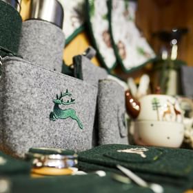 Nahaufnahme von verschiedenen Souvenirs aus grünem und grauen Filz mit Hirsch Stickerei wie Schlüsselanhänger, Flaschenhülle und Geldbörse 