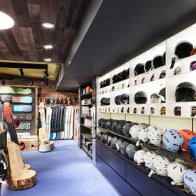 Innenansicht vom Shop im Take Off mit einer großen Auswahl an Helmen. Im Hintergrund stehen Snowboards von Burton und Nitro