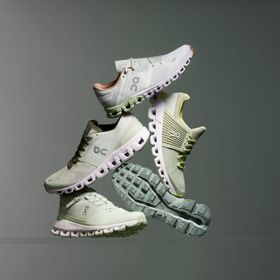 verschiedene Schuhmodelle der Marke On in der Farbe mint, creme und Beige vor einem grau- weißen Hintergrund