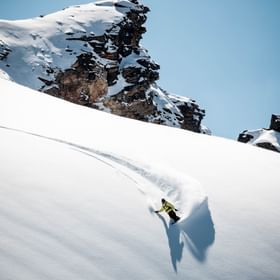 Ein Snowboarder macht mit seinem Snowboard im tiefen Schnee im Gelände einen riesigen Spray