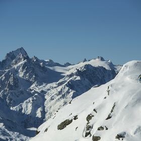 Eine Gruppe Tourengehern laufen mit Tourenski einen tiefverschneiten Berghang zum Gipfel hinauf 