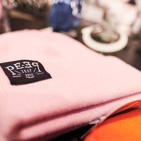Nahaufnahme einer Mütze in rosa mit einem Patch vom hauseigenen Peep Shop Label