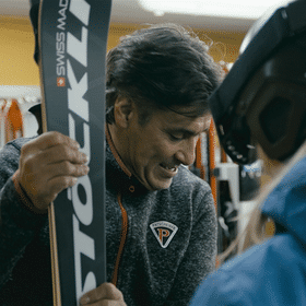 Ein Mitarbeiter gibt einer Skifahrerin ihren Ski aus dem Depot im Check in in Serfaus