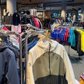 Eine große Auswahl an Markenware wie Skibekleidung von Scott, Moncler, The Mountain Studio, Ortovox, Kjus, funktionaler Bekleidung und vielen anderen Accessoires zum Skifahren, Wandern oder Radfahren für Frauen, Männer und Kinder im Outlet im Check In Bikecenter Serfaus