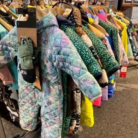 Kinderschneeanzüge hängen auf einer Kleiderstange im Outlet im Check In Bikecenter Serfaus
