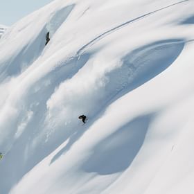 Eine Gruppe von Snowboardern fährt im Tiefschnee im Gelände 
