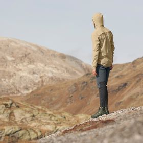 Ein Mann steht in einer Berglandschaft mit On Bekleidung, Jacke und Laufschuhen 