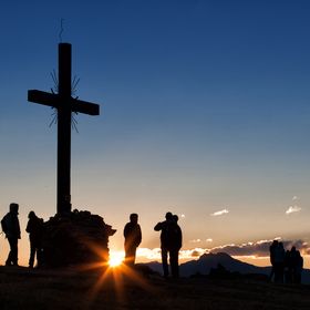 Eine Gruppe von Wanderern erreicht das Gipfelkreuz am Furgler im Sonnenaufgang