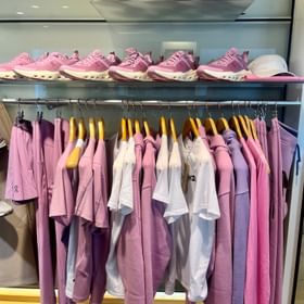 Im On Shop ist eine Wand mit rosa Shirts und Hoodies und passenden On Schuhen dekoriert