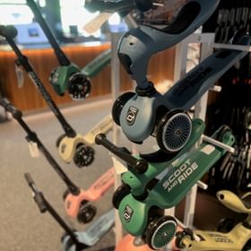 Im Geschäft stehen Tretroller Modelle der Marke Scoot für Kinder in verschiedenen Größen und Farben zum Verkauf