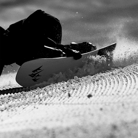 Ein Mann carved auf einer Piste mit einem Jones Snowboard