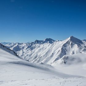 Winterliches Bergpanorama mit tief verschneiten Berghängen und Gipfeln und blauem Himmel im Skigebiet Serfaus-Fiss-Ladis 