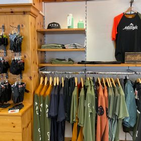 Im modern eingerichteten Innenraum des Geschäfts gibt es Fahrradbekleidung, Caps und Trinkflaschen der Marken Maloja und Scott für Herren