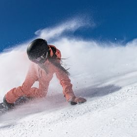 Eine Frau carved auf der Piste auf einem Burton Snowboard