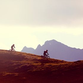 Eine Gruppe fährt auf Mountainbikes einen Bergtrail in Serfaus-Fiss-Ladis im Sonnenuntergang