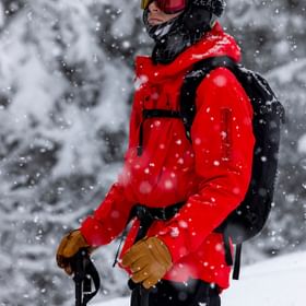 Ein Freerider steht im Wald im Schneegestöber auf Ski und blickt in die Landschaft