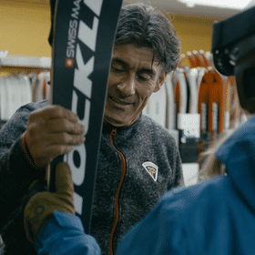 Ein Mitarbeiter gibt einer Skifahrerin ihren Ski aus dem Depot im Check In in Serfaus