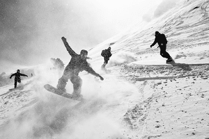 Partywaves garantiert mit der Jones Snowboard Surf Series Eine Gruppe von Snowboardern fährt zusammen im verschneiten Gelände