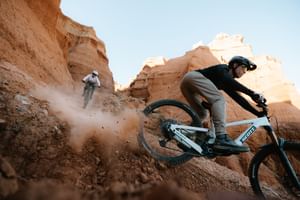 Ein Mann und eine Frau fahren auf Scott E-Bikes einen Trail in felsiger Landschaft hinunter