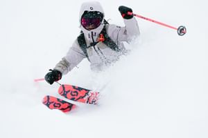 Eine Freeriderin fährt im tiefen Pulverschnee einen steilen Hang hinunter
