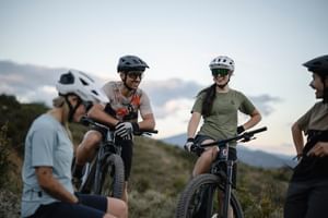Eine Gruppe von Mountainbikern steht in einer hügeligen Landschaft mit Mountainbikes zusammen und macht eine Pause