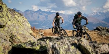 Zwei Männer fahren mit Fully Mountainbikes von Scott einen Trail durch eine raue Berglandschaft