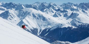 Ein Freerider fährt im tiefen Pulverschnee einen steilen Hang im Skigebiet von Serfaus hinunter