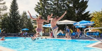 Zwei Mädchen springen vom Beckenrand in den Pool