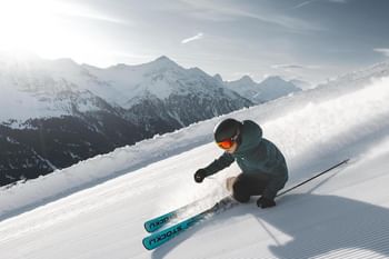 Lässige Schwünge auf und abseits der Piste mit Patscheider Sport Eine Skifahrerin carved mit einem Ski der Marke Stöckli auf einer frisch präparierten Skipiste.