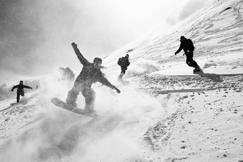Partywaves garantiert mit der Jones Snowboard Surf Series Eine Gruppe von Snowboardern fährt zusammen im verschneiten Gelände