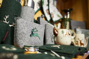 Nahaufnahme von verschiedenen Souvenirs aus grünem und grauen Filz mit Hirsch Stickerei wie Schlüsselanhänger, Flaschenhülle und Geldbörse 