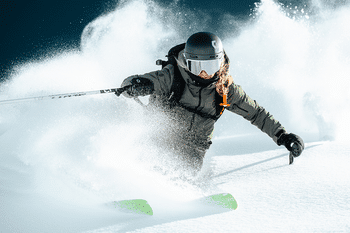 Eine Freeriderin fährt im tiefen Pulverschnee einen steilen Hang hinunter