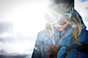 Eine Frau in Skibekleidung und mit Helm und Brille in Nahaufnahme mit Sonneneinstrahlung