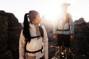 Ein Mann und eine frau stehen im strahlenden Sonnenlicht auf einem Gipfel und blicken in die Ferne