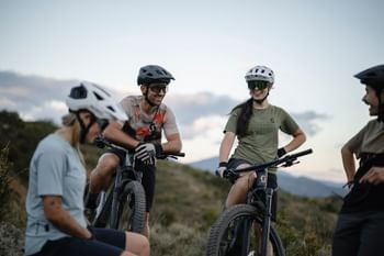 Eine Gruppe von Mountainbikern steht in einer hügeligen Landschaft mit Mountainbikes zusammen und macht eine Pause