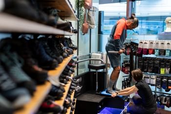 Eine professionelle Schuhverkäuferin vermisst mit einem Gerät im die Fußabdrücke eines Kunden für die Schuhanpassung