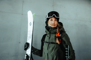 Eine Frau steht in Scott Skibekleidung und mit Scott Freerideski in einer Seilbahnstation