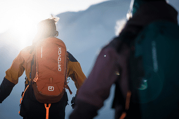 Zei Tourengeher laufen auf Tourenski mit einem Ortovox Rucksack einen Berg hinauf