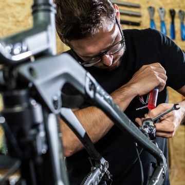 Ein Mitarbeiter macht einen Fahrradservice an einem Mountainbike in der Werkstatt
