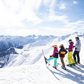 Eine Familie steht am Rand einer Piste im Skigebiet Serfaus und schaut in die weiße Berglandschaft