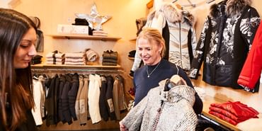 Eine Verkäuferin berät eine Kundin beim Kauf einer Sportalm Jacke im Patscheider Sport Geschäft in der Modeabteilung in Serfaus