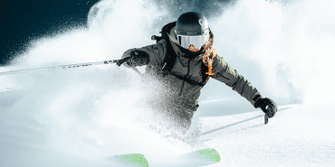 Eine Freeriderin fährt im tiefen Pulverschnee einen steilen Hang hinunter