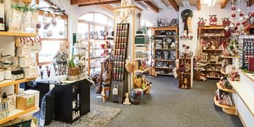 Innenansicht vom Geschäft mit Regalen die mit verschiedenen Wohnaccessoires wie Kerzenhalter, Vasen, Figuren und Seifen und anderen Souvenirs dekoriert sind